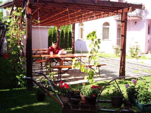 a man sitting at a picnic table under a pergola at Vila Madams - Palić-Serbia in Palić
