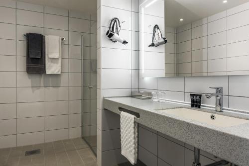 La salle de bains blanche est pourvue d'un lavabo et d'un miroir. dans l'établissement Clarion Collection Hotel Victoria, à Jönköping