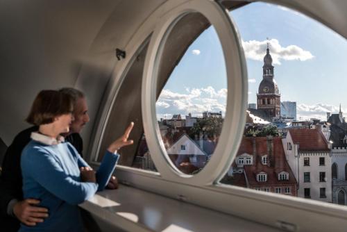 two women standing in a window looking at a city at Relais Le Chevalier in Rīga