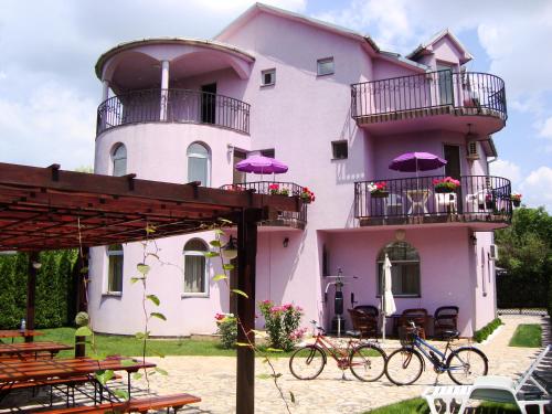 um edifício cor-de-rosa com bicicletas estacionadas em frente em Vila Madams - Palić em Palić