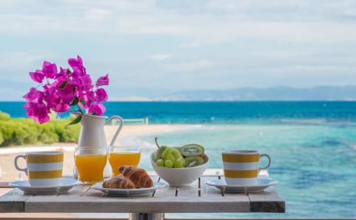a table with a plate of food and two glasses of orange juice at Oasis Beach Hotel in Skala