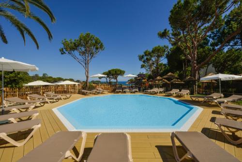 a swimming pool with chairs and umbrellas at 3HB Falésia Garden in Albufeira