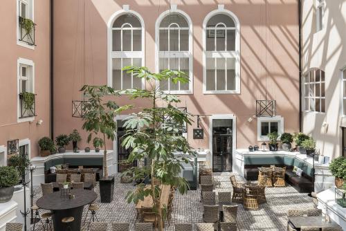 un patio de un edificio rosa con mesas y plantas en Clarion Collection Hotel Victoria, en Jönköping