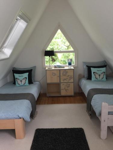 a attic room with two beds and a window at Bed & Breakfast Kortenhoefsedijk in Kortenhoef