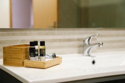 a bathroom sink with a wooden box of makeup brushes at Spot Apartments Trindade in Porto