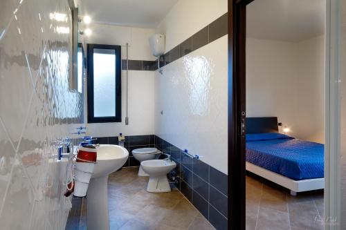 a bathroom with a sink and a toilet and a bed at Su AlevraXi in Villagrande Strisaili