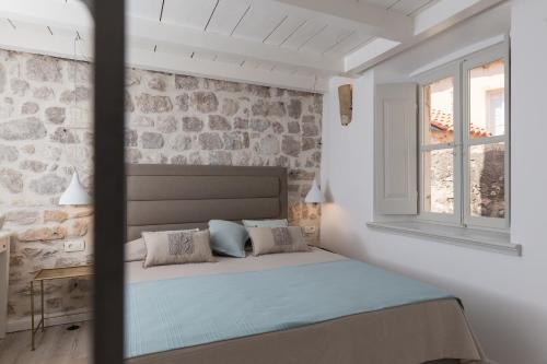 a bed in a room with a stone wall at Dubrovnik Sweet House in Dubrovnik