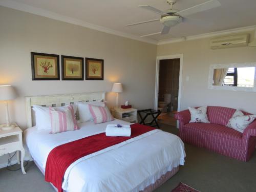 1 dormitorio con 1 cama grande y 1 sofá rojo en The Beach House, en Port Alfred