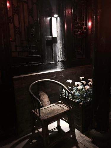a chair in a dark room with a basket of flowers at Elsewhere Hotel The former residence of the draft bank in Pingyao