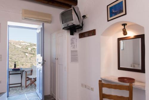 a room with a tv on the wall and a table at Aris & Maria Houses in Kastron