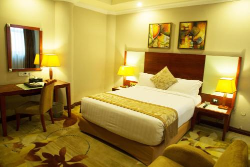 a hotel room with a large bed and a desk at Jupiter International Hotel - Bole in Addis Ababa