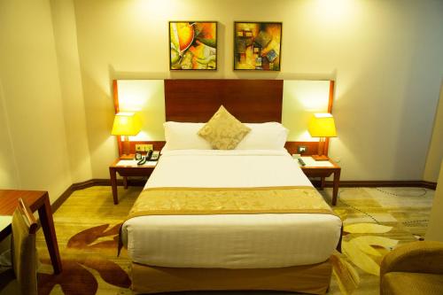a bedroom with a bed and two tables and two lamps at Jupiter International Hotel - Bole in Addis Ababa