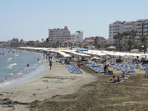 people on a beach with chairs and umbrellas at Marina's Rooms in Larnaka