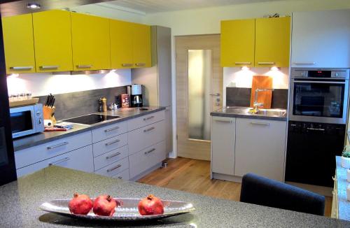 a kitchen with yellow cabinets and pomegranates on a counter at Komfortwohnung City/Messe 25 Min in Cologne
