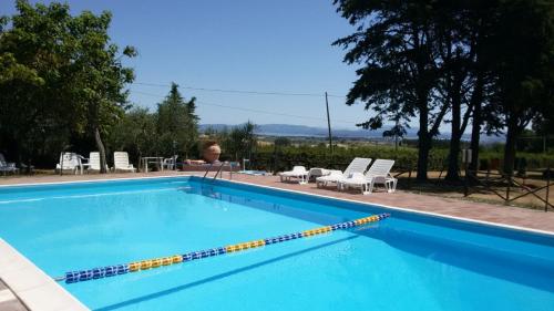 una gran piscina azul con sillas y mesas. en Agritur Villa Osvaldo Castiglione Lago PG Piscina acqua salata, en Castiglione del Lago