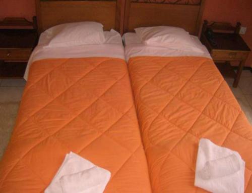 Una cama naranja y blanca con dos almohadas. en Hotel Stadion, en Delfos