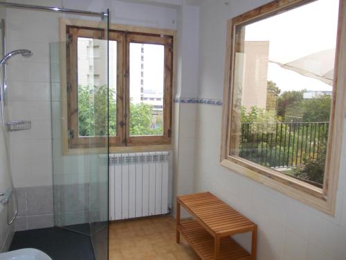 a bathroom with a shower and a bench and two windows at La Posada de San Marcial in Tudela