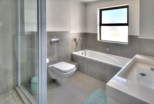 a bathroom with a toilet and a tub and a sink at Azure 216 in Bloubergstrand