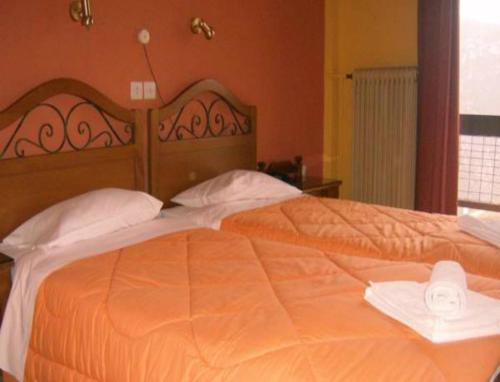 a bedroom with a large orange bed with a hat on it at Hotel Stadion in Delphi