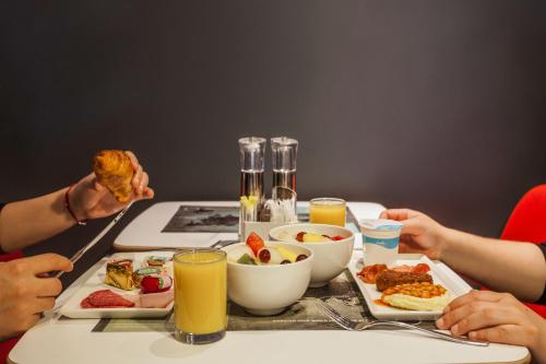 two people sitting at a table with food and drinks at ibis London Excel-Docklands in London