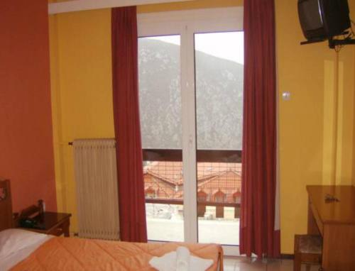 a bedroom with a large window with red curtains at Hotel Stadion in Delfoi