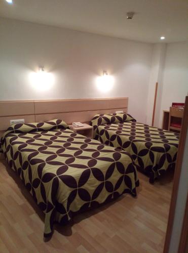two beds in a hotel room with lights on the wall at Nap Carta Puebla in Oviedo