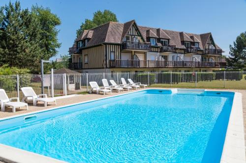une maison avec piscine devant un immeuble dans l'établissement Résidence Goélia Green Panorama, à Cabourg