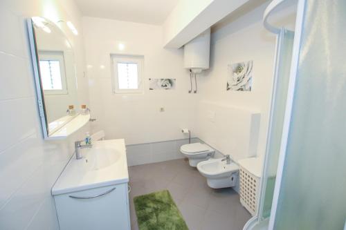 a white bathroom with two toilets and a sink at Apartman Mila in Poreč
