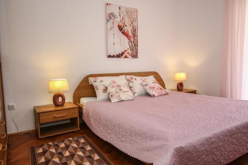 a bedroom with a bed with pink sheets and pillows at Apartman Mila in Poreč