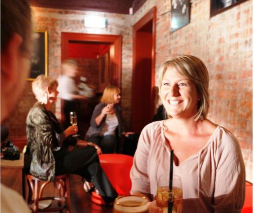 a woman sitting at a table in a room at The Hotel Shamrock in Bendigo