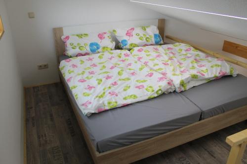 Cama en habitación pequeña con ropa de cama blanca y rosa en Ferienwohnung Lauenbrück, en Lauenbrück