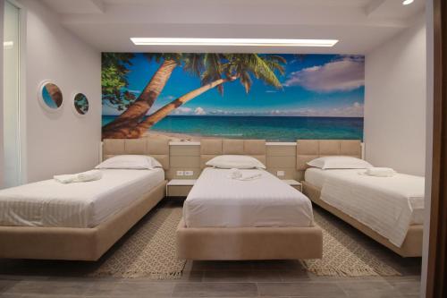 two beds in a room with a palm tree mural at Hotel Kristera in Vlorë