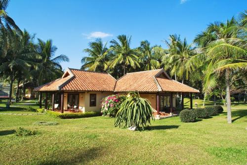 a house in a yard with palm trees at Seahorse Resort & Spa in Mui Ne