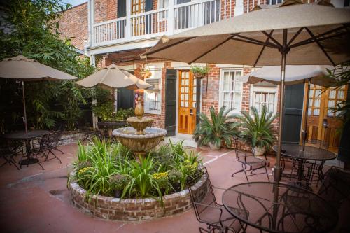 an outdoor patio with tables and chairs and an umbrella at Inn on St. Ann, a French Quarter Guest Houses Property in New Orleans