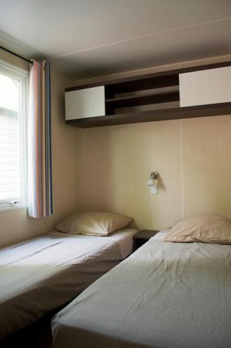 two beds in a room with a window at DS One Vacances, Prairies de la Mer in Grimaud