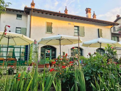 a building with umbrellas and flowers in front of it at B&B La Borasca - Rooms in Casalpusterlengo