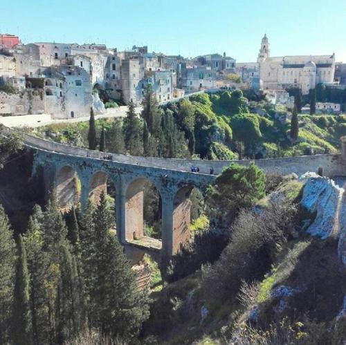 a bridge on a hill with a city in the background at Giardini 82 B&B in Gravina in Puglia