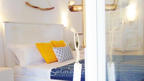 una camera da letto con un letto bianco con cuscini gialli di SalinaRelais Rooms&Suite a Malfa