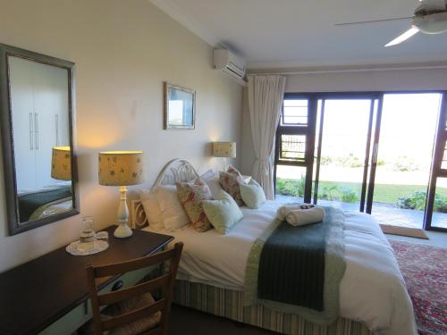 Un dormitorio con una cama, un escritorio y ventanas. en The Beach House, en Port Alfred