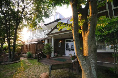 a house with a bench on the front yard at Pension Angelica in Minami Aso