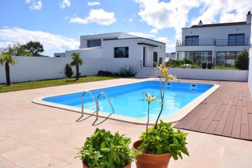 a villa with a swimming pool in front of a house at Casa Cidade Lagoa - Pool,Jacuzzi family& friends in Rosário-Lagoa