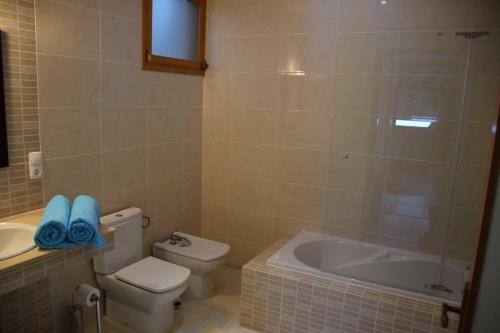 a bathroom with a toilet and a tub and a sink at Casa Cidade Lagoa - Pool,Jacuzzi family& friends in Rosário-Lagoa