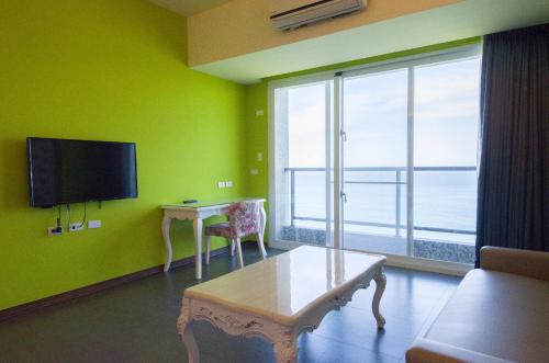 a living room with a green wall with a table and a television at Whitecaps B&B in Yanliau