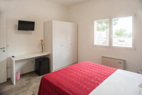 a bedroom with a bed and a desk and a window at Blu Salentino in Porto Cesareo