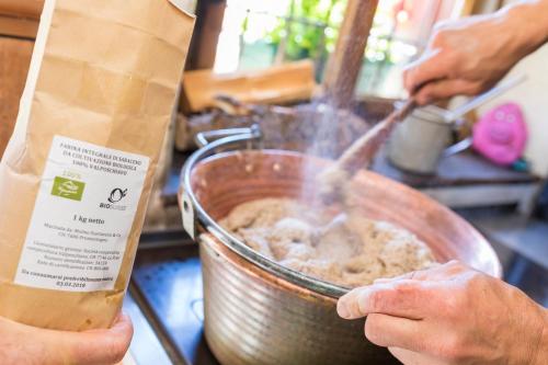 a person preparing food in a pot on a counter at Rifugio Alpe San Romerio in Brusio