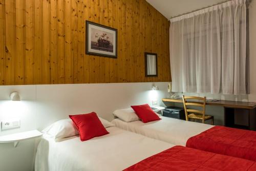 Cette chambre d'hôtel comprend 2 lits avec des oreillers rouges. dans l'établissement Fasthotel Thones, à Thônes