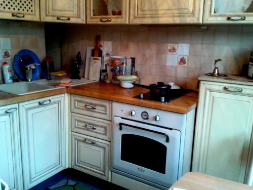 a kitchen with white cabinets and a white stove top oven at Rooms in Apartment on Tbilisskiy bulvar 11 in Yekaterinburg