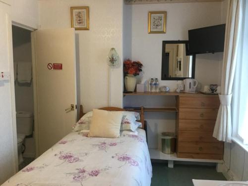 um quarto com uma cama, uma cómoda e um espelho em The Hotel Wilmar em Blackpool