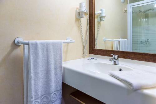 a white bathroom with a sink and a mirror at Fasthotel Thones in Thônes