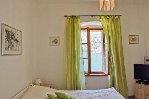 um quarto com uma janela com cortinas verdes e uma cama em Ribica Apartments em Kotor